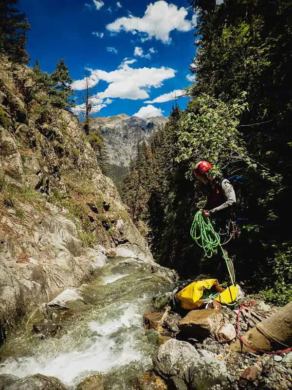 Guide preparing to set up the ropes for canyoneering in Ouray while a small rapid rushes before him.