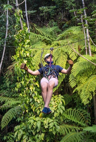 Latino man on a zip line in Costa Rica against green follage