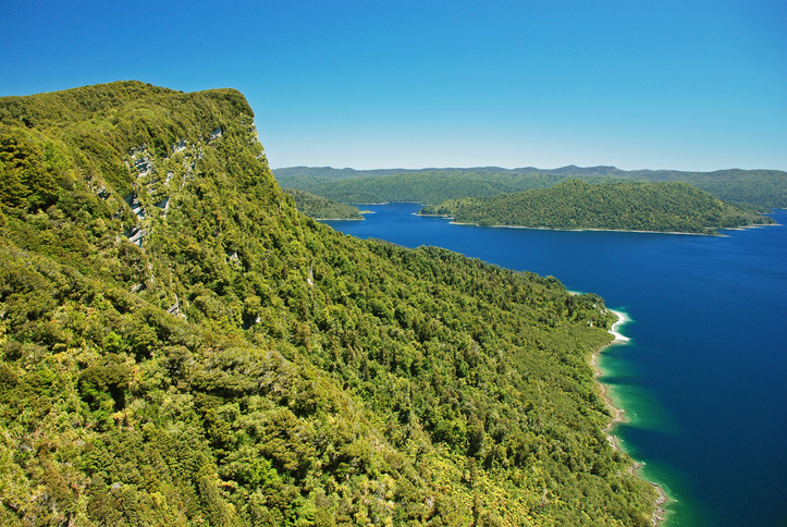 The blue lake Waikaremoana surrounded by green hills is located in Te Urewera National Park in the North Island of New Zealand.