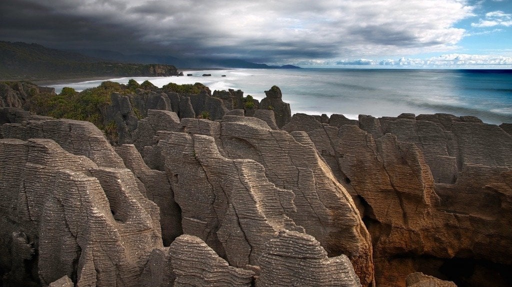 View of rugged sharp-looking limestone rock formation on the coastline. The formations are in the foreground, while the sea is in the background. 