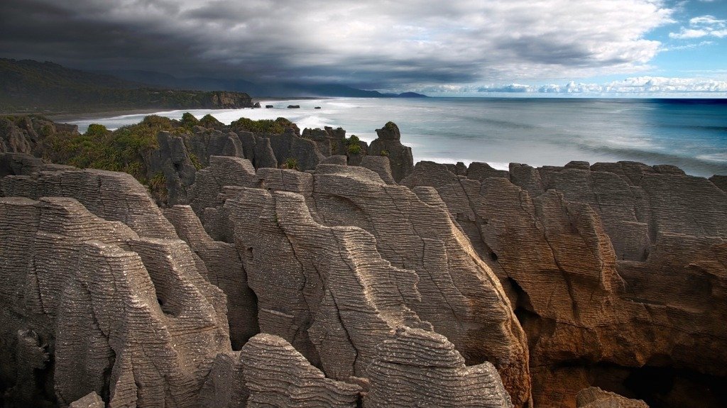 View of rugged sharp-looking limestone rock formation on the coastline. The formations are in the foreground, while the sea is in the background. 