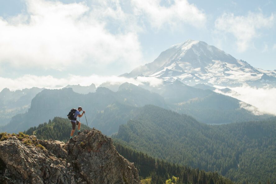 Hiker on a rocky outcropping with Mount Rainier in the background