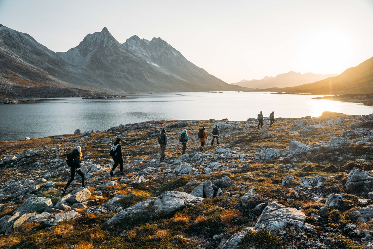 Hikers walking across a meadow during sunset