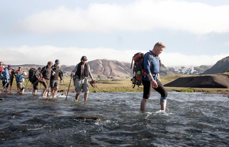 Hikers traversing the river crossing in Iceland.