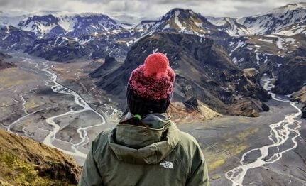 A hiker standing in front of the Thorsmork valley and its snaking rivers