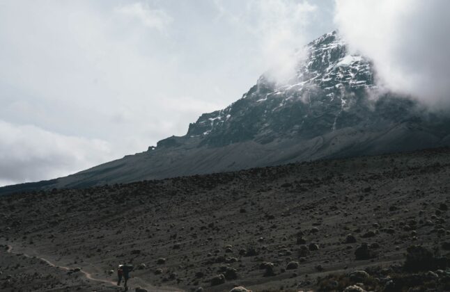 Two hikers staring across the Shira Ridge with Mount Kilimanjaro in the background.