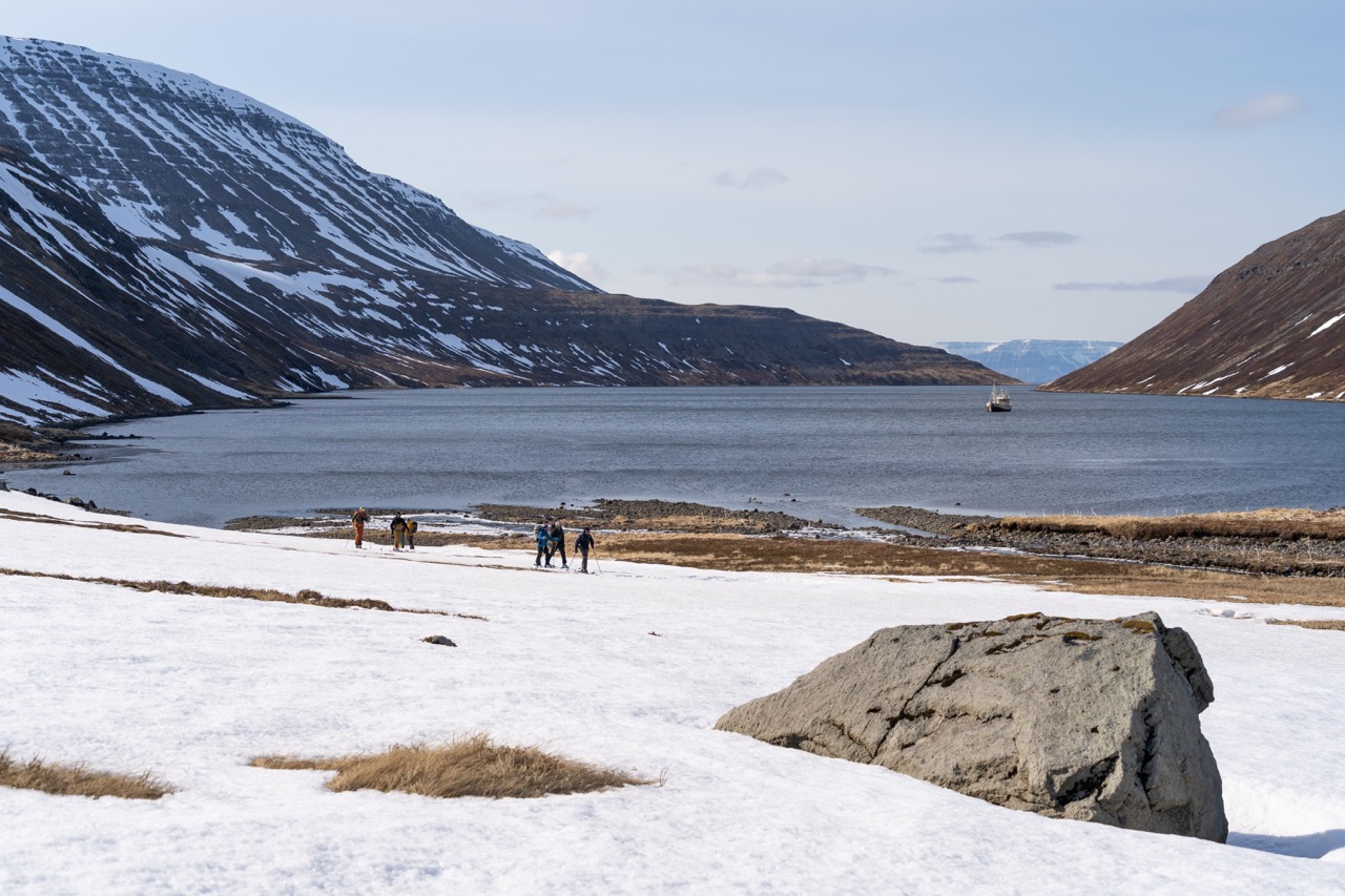 Skiers on the shore with sea in the background