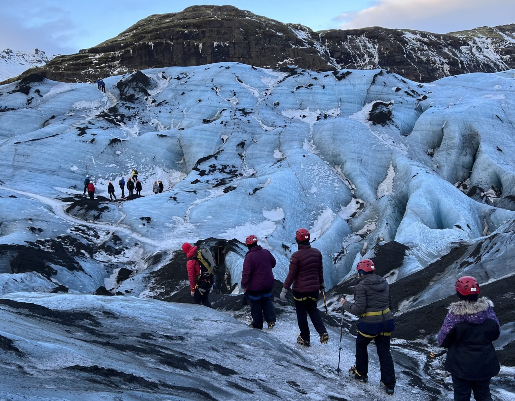 A group of hikers follow each other in a line, crossing over Solheimajokull glacier