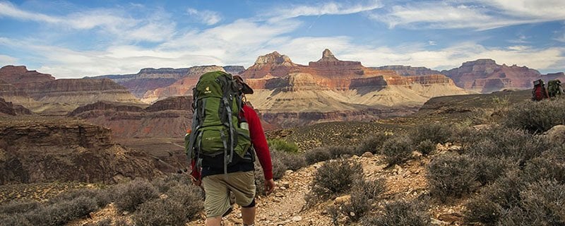 A hiker walking among arid landscapes of the Grand Canyon.