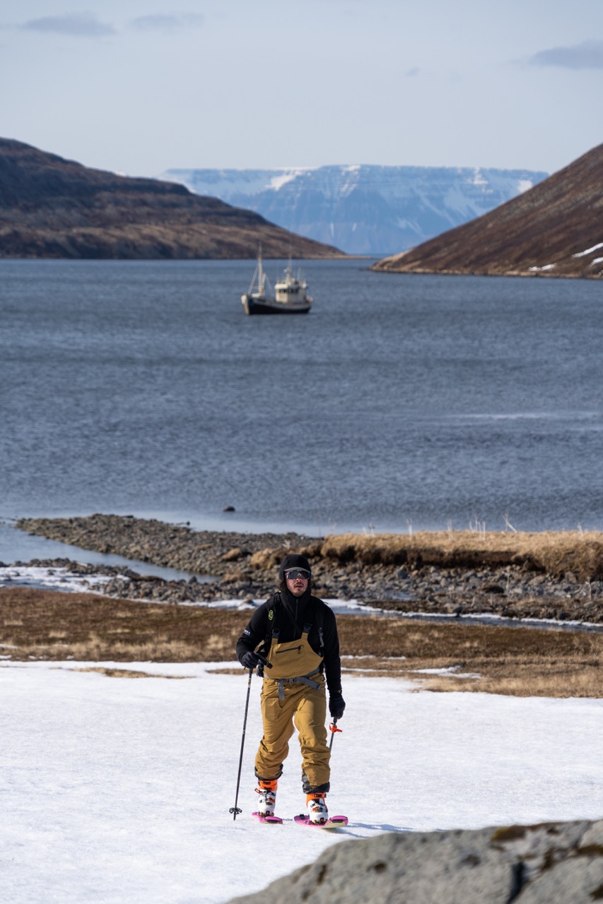 A man skinning with the sailboat in the background