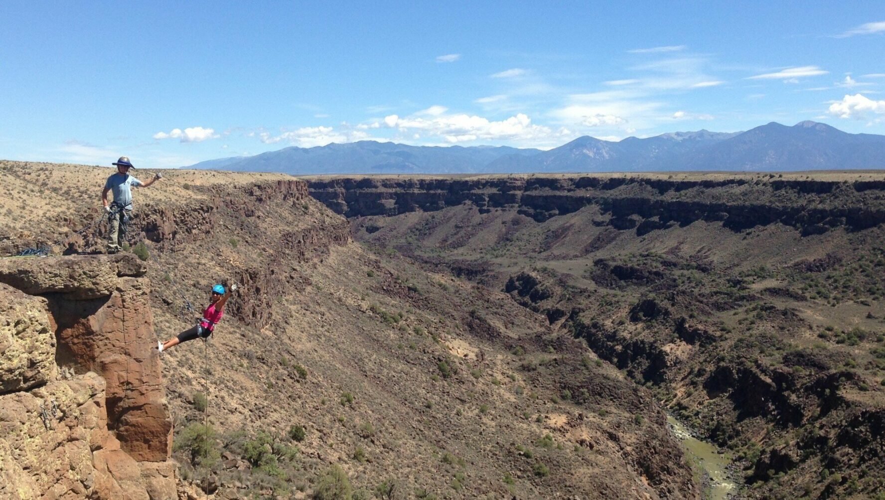 Two rock climbers on the edge of a cliff.