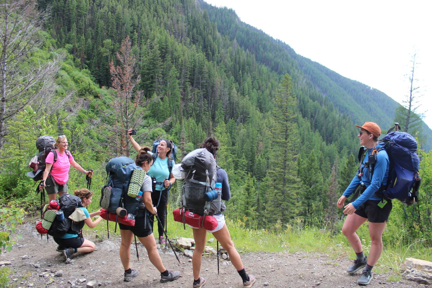 Happy backpackers on a trail with greenery in Whitefish, Montana