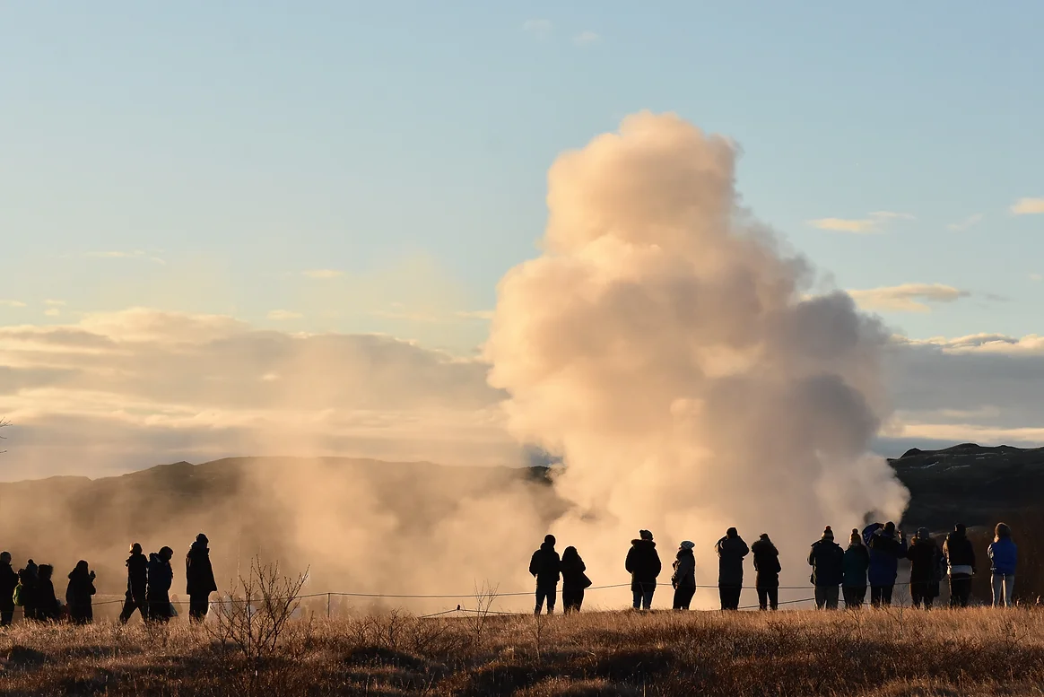 Visitors admiring a geyser eruption in Iceland.