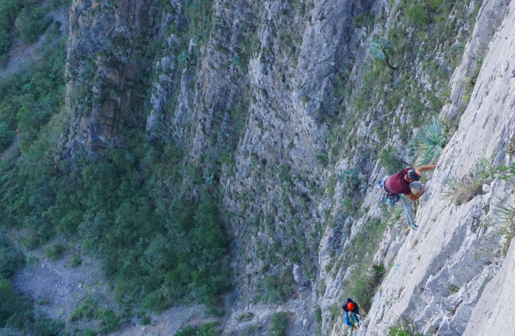 Two climbers in the middle of a very long ascent up a vertical limestone wall at El Potrero Chico.