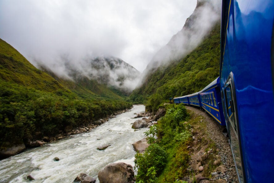 The distinctively blue Peru Rail train running next to the Urubamba River.