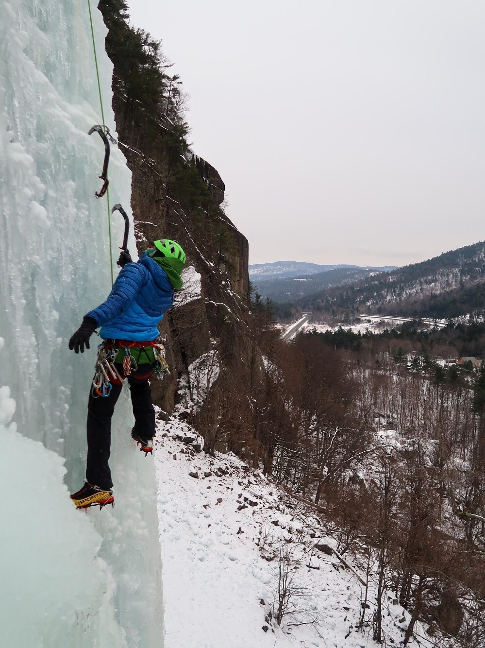 An ice climber posing next to a scenic vista in New England.