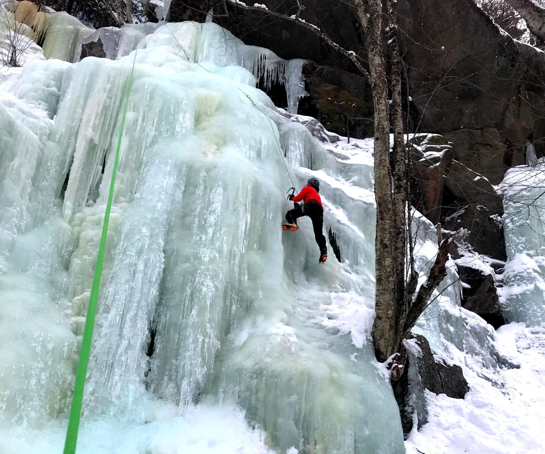 A climber receiving ice climbing instruction on an ice wall in New England.