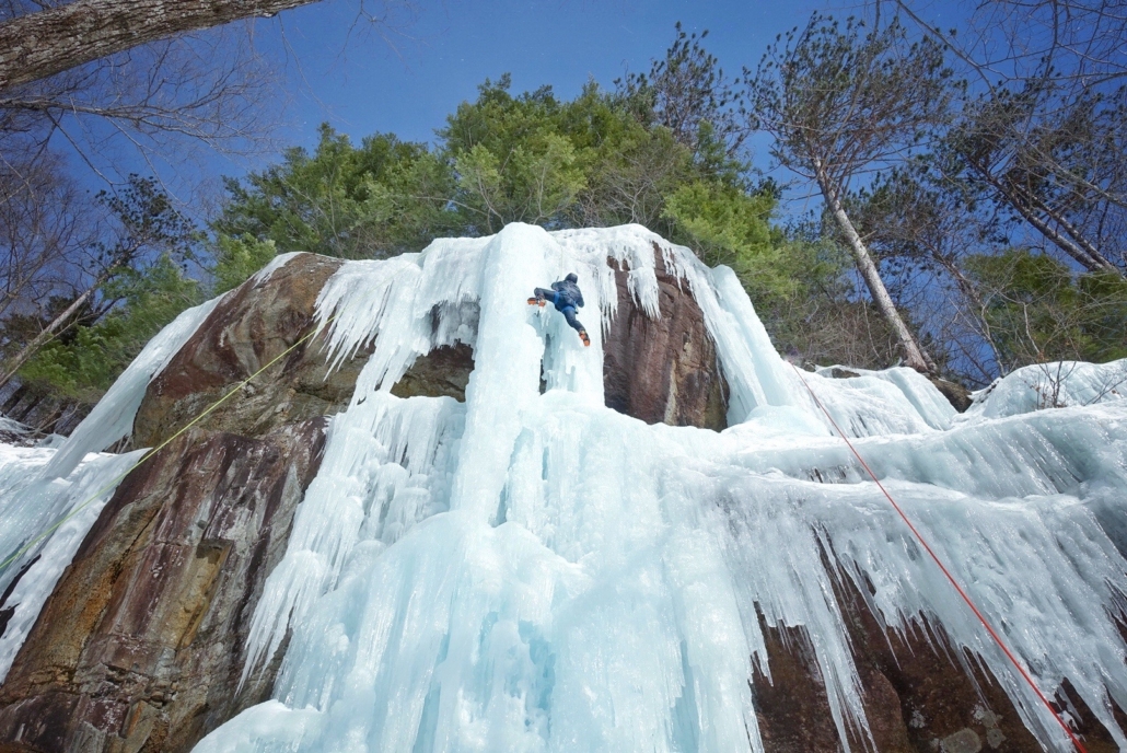 Ice climber scaling a frozen waterfall in New Hampshire.