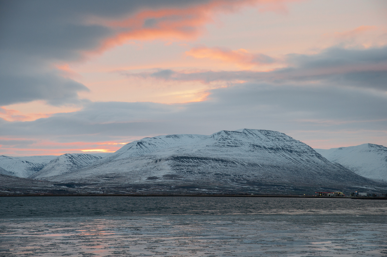 View of a snow-covered mountain in the Troll Peninsula with ocean in the front during sunset.