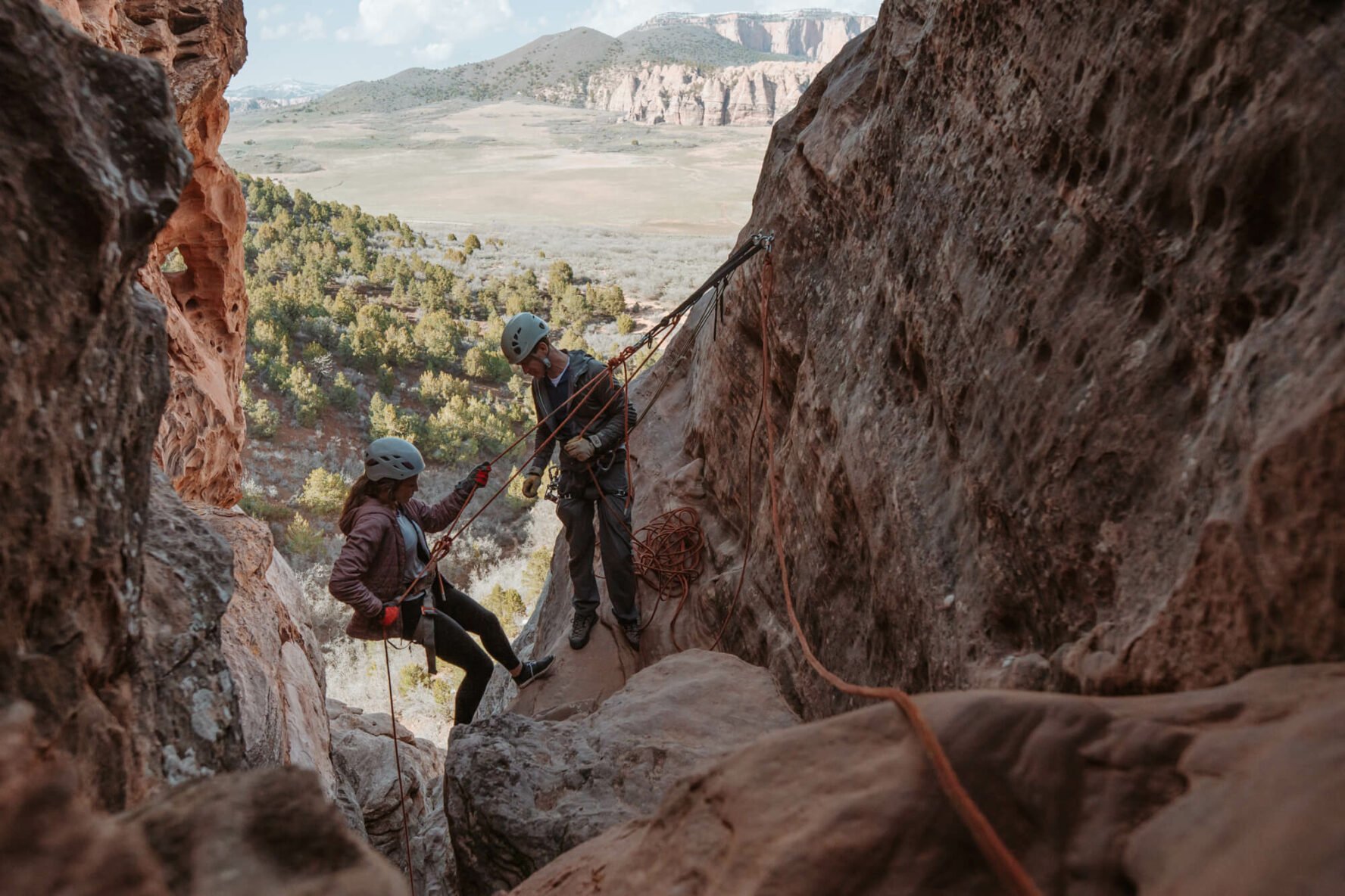 A beginner climber and canyoneer is rappelling in Zion while being instructed by the guide.