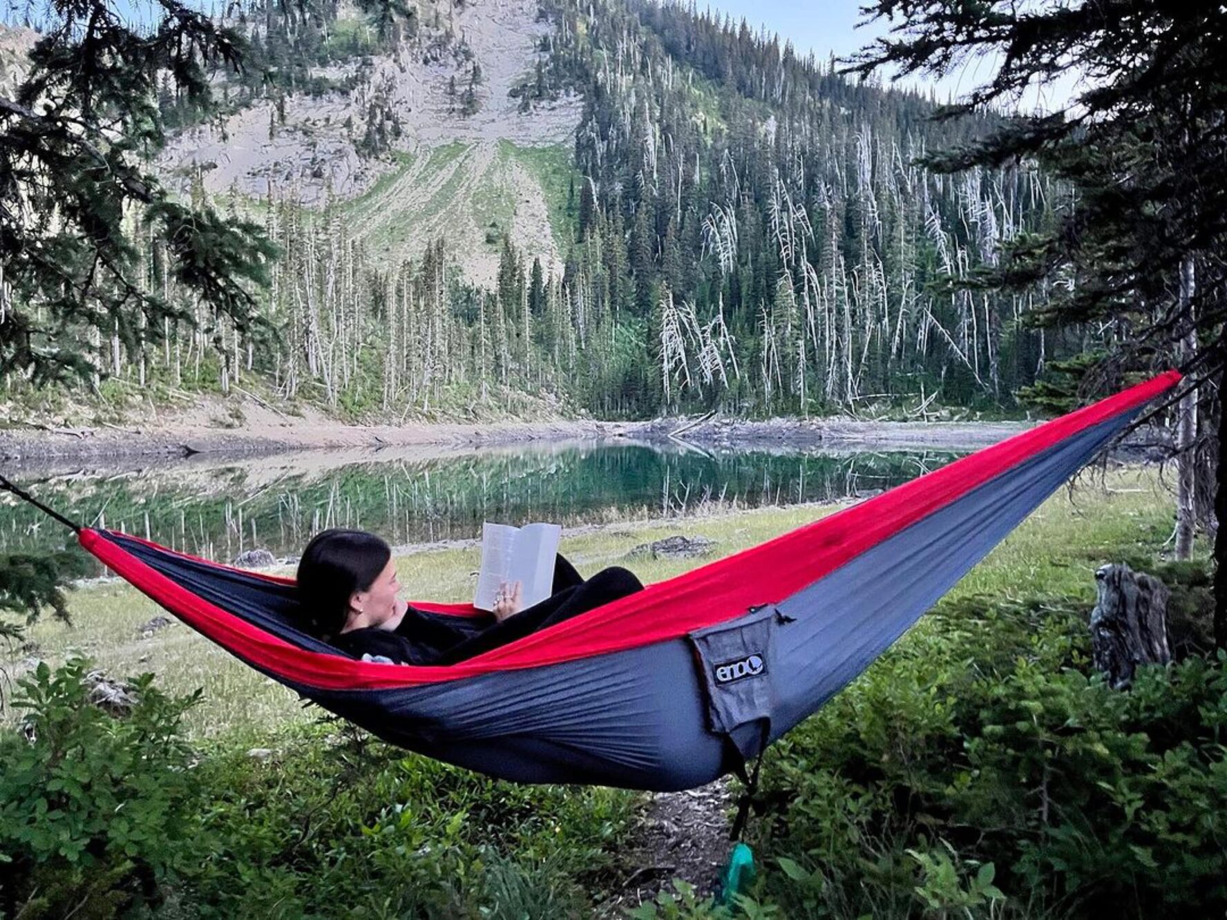 A person resting in a hammock with mountains in the background