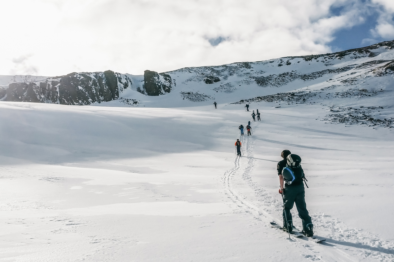 A group of backcountry skiers skinning up a gradual slope in the Troll Peninsula in North Iceland.