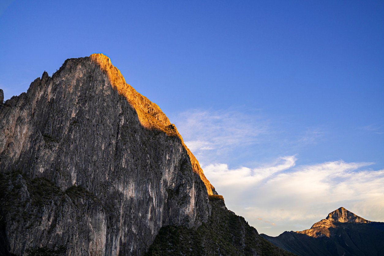 Tops of large limestone formations at El Potrero Chico illuminated during sunset.