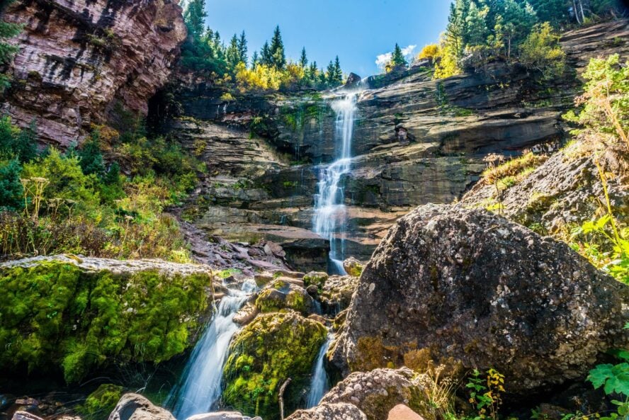 Bear Creek Falls seen from the base of the waterfall as the beautiful canyon and mossy covered rock rises up around it. 