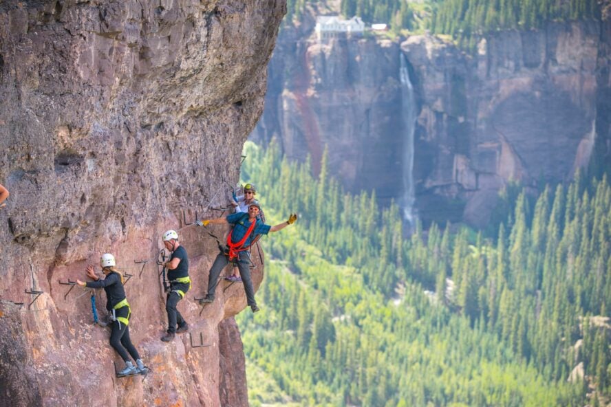 People walk on the Telluride Via Ferrata route above the fall colors of the box canyon below on an overcast fall day. 