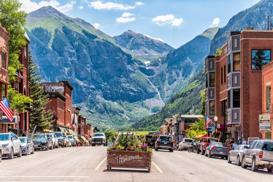 Brick buildings line the streets of downtown Telluride on a summer's day as the mountains linger in the background