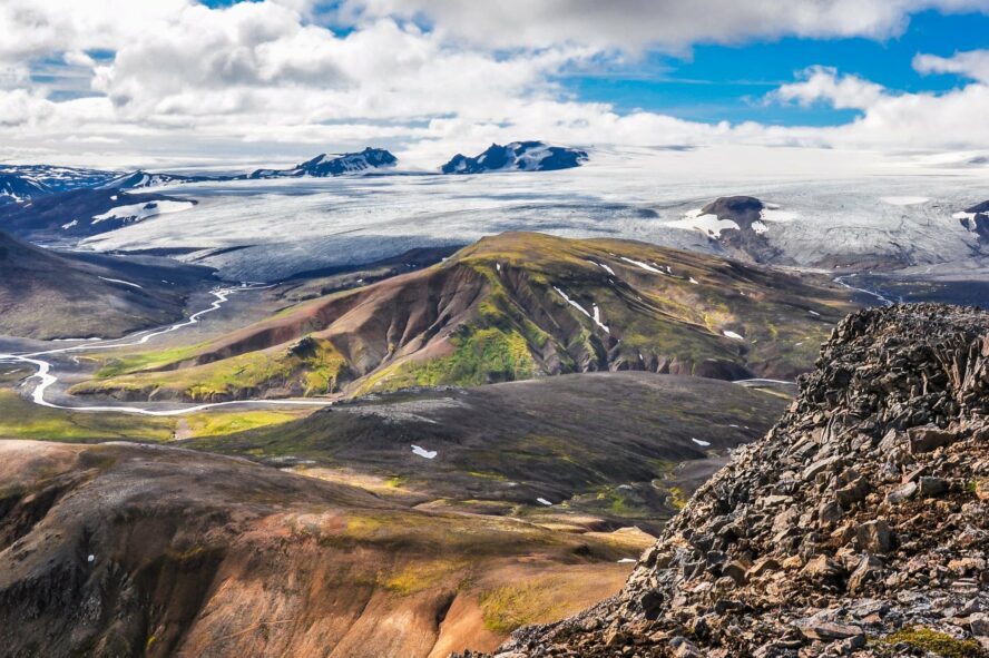The contrasting landscape of Iceland from orange and green meadows to black and white mountains