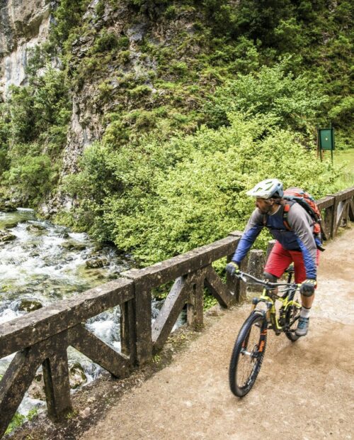 Mountain bikers on the Camino Primitivo in Spain by a river.