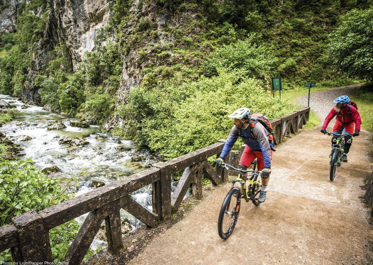 Mountain bikers on the Camino Primitivo in Spain by a river.