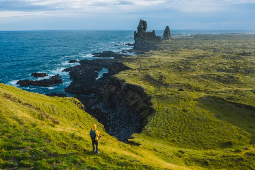 Hiker standing on the basalt cliffs of Lóndrangar above the Atlantic Ocean