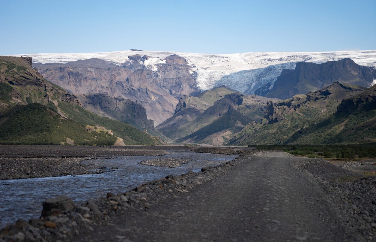 Bank of the Krossa river and mountains with a hanging glacier in the distance.