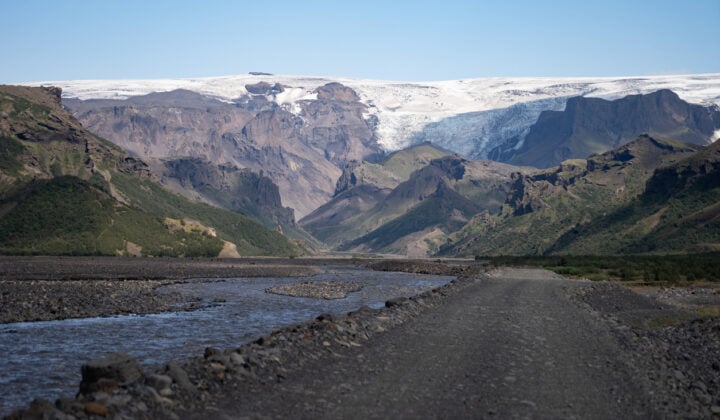 Bank of the Krossa river and mountains with a hanging glacier in the distance.