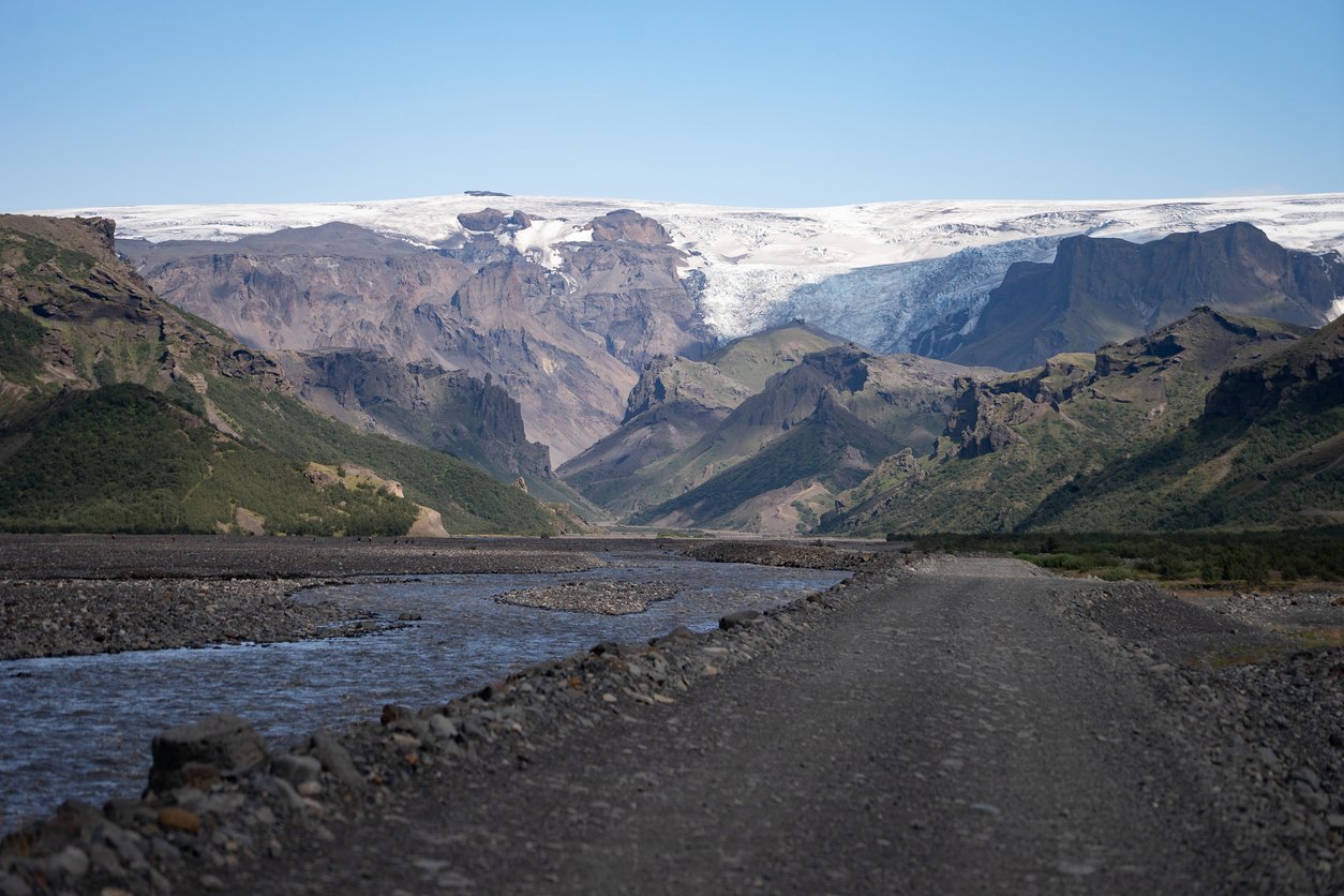 Bank of the Krossa river and mountains with a hanging glacier in the distance.