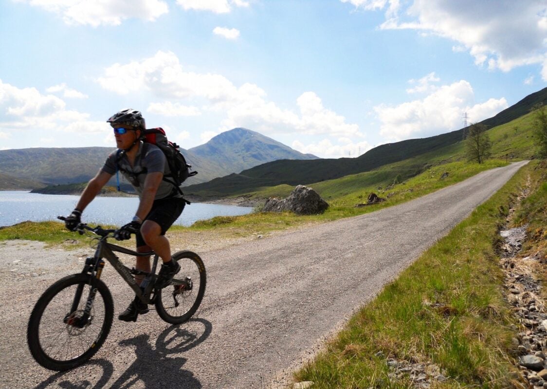 A mountain biker riding along a loch-side path in Scotland. 