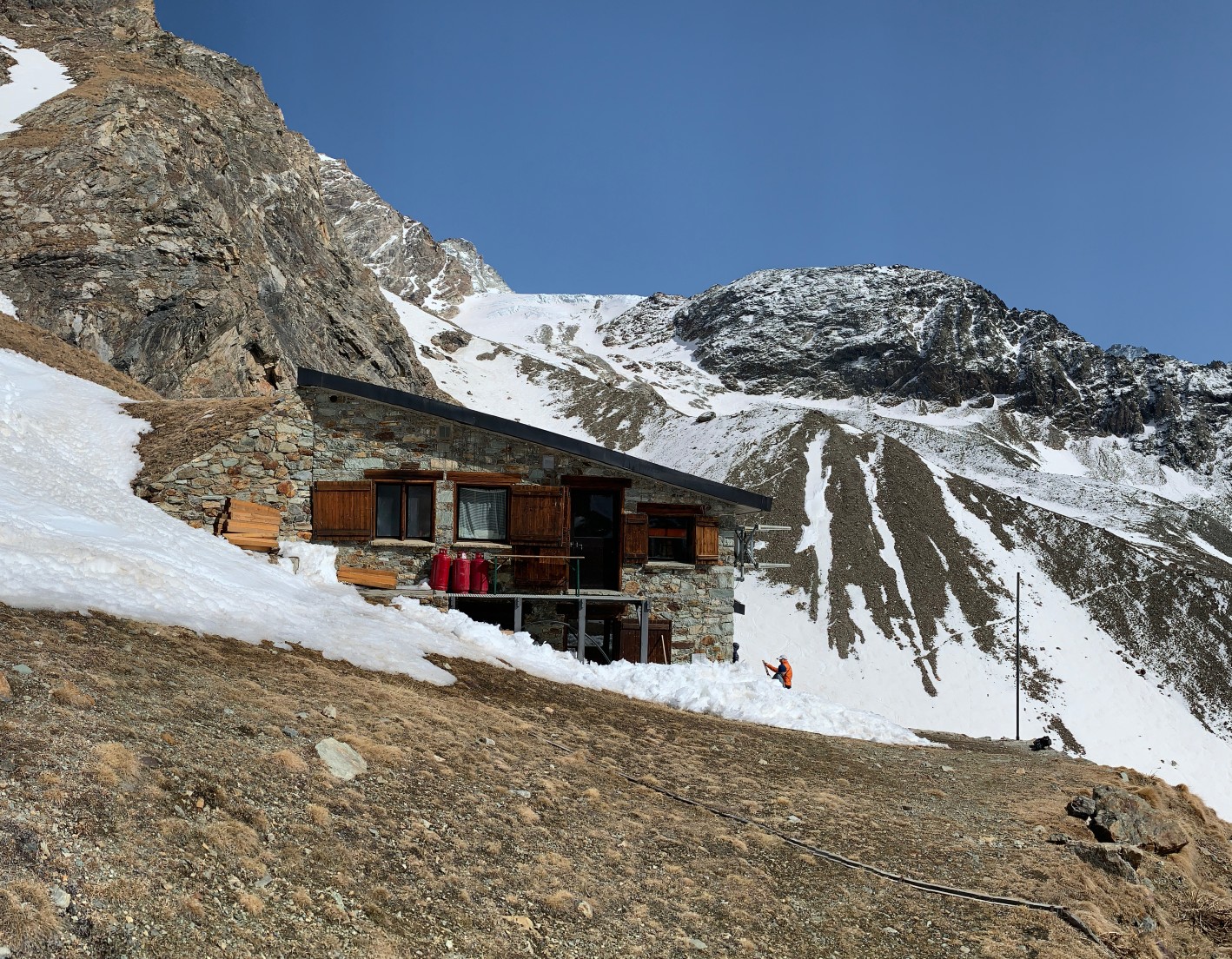 A quaint stone mountain hut at the foot of an Alpine peak in the Valpelline Valley.