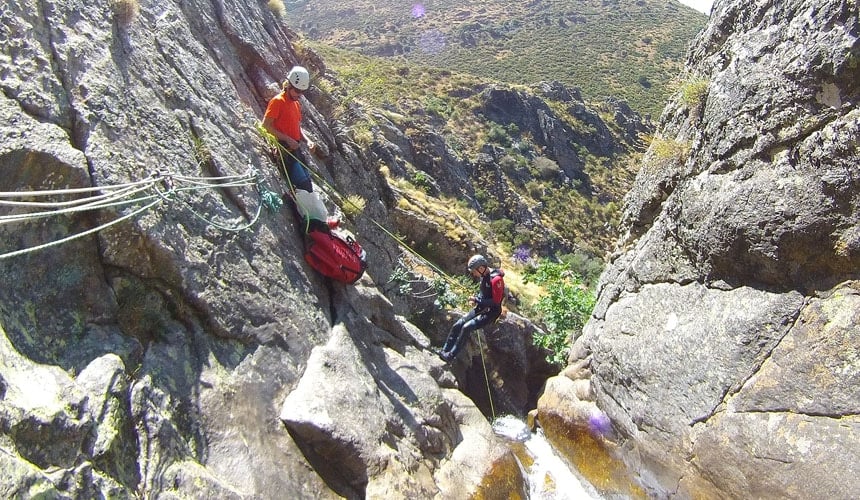 A canyoneer having a crack at repelling supervised by their guide during a canyoning adventure near Madrid.