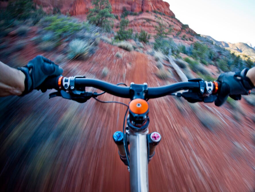 POV shot of a mountain biker shredding a red dirt trail