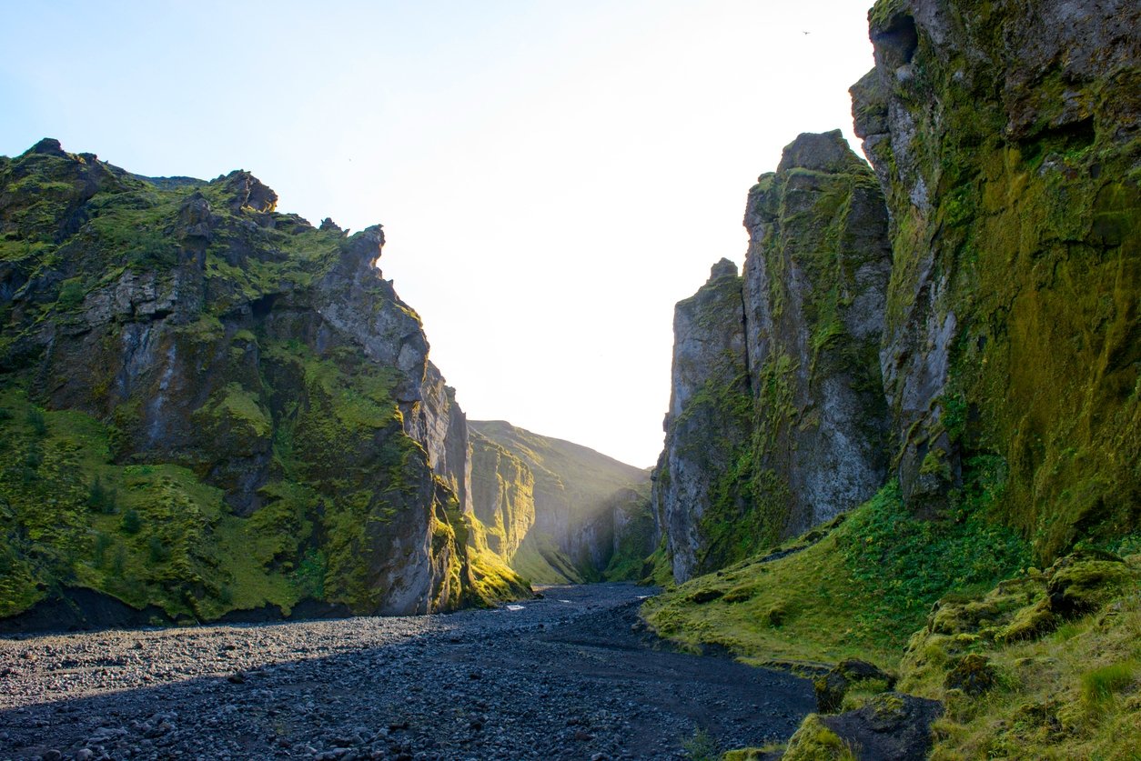Sveinstindur canyon enclosed by massive granite walls covered in moss.
