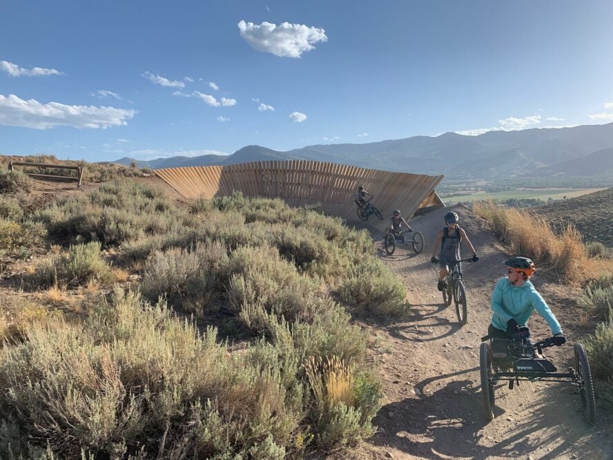 Mixed group of riders tackling a wooden berm feature.