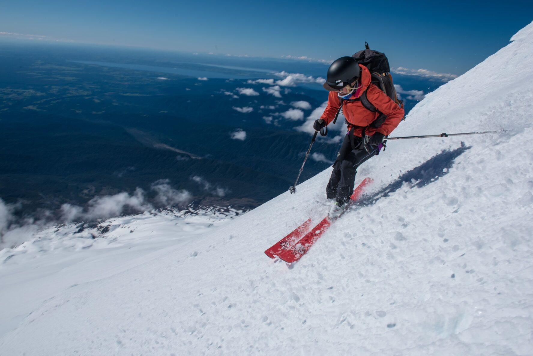 Skier making a sharp turn on a downhill descent on an Andean volcano.