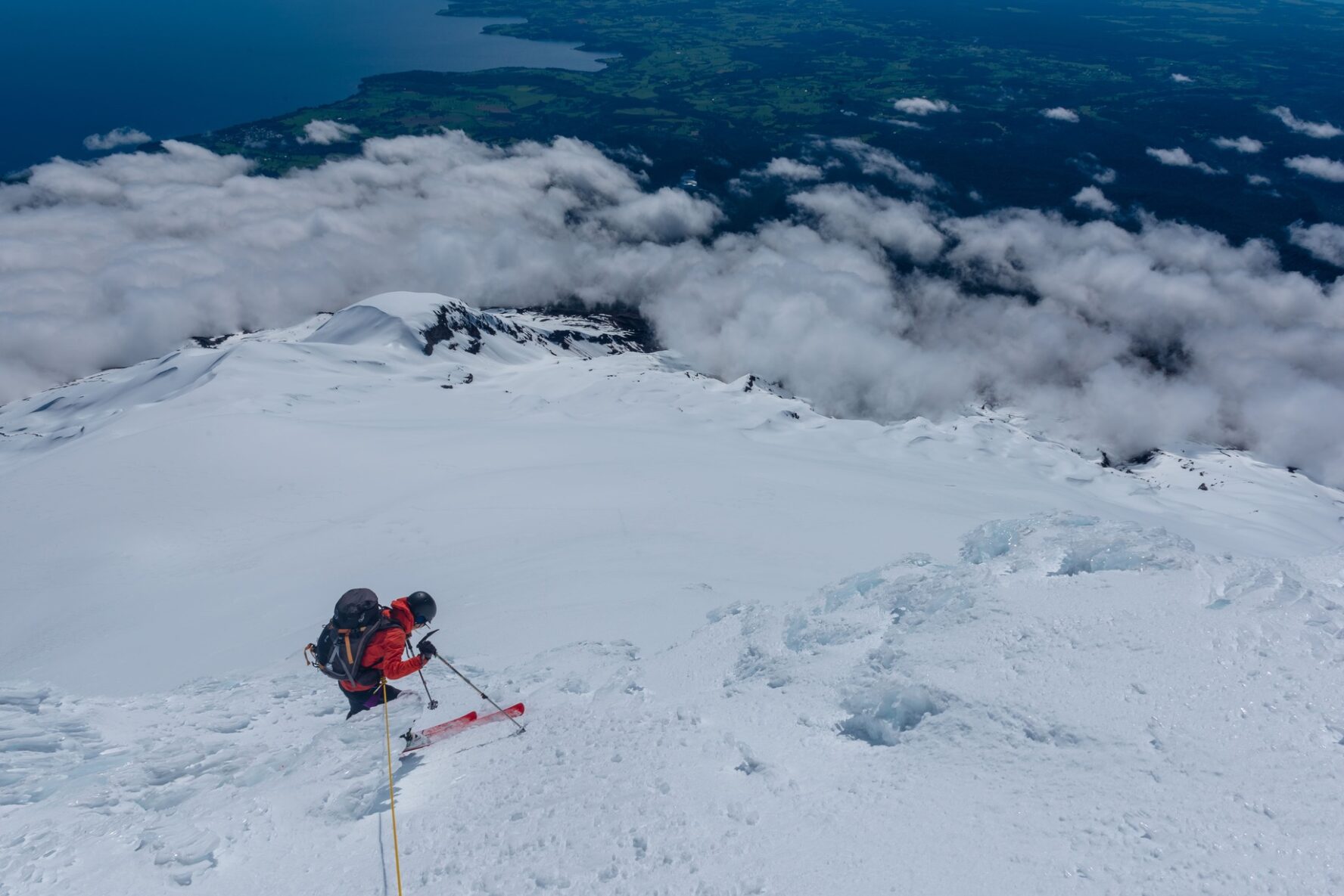 A skier above the clouds skiing on a difficult slope.