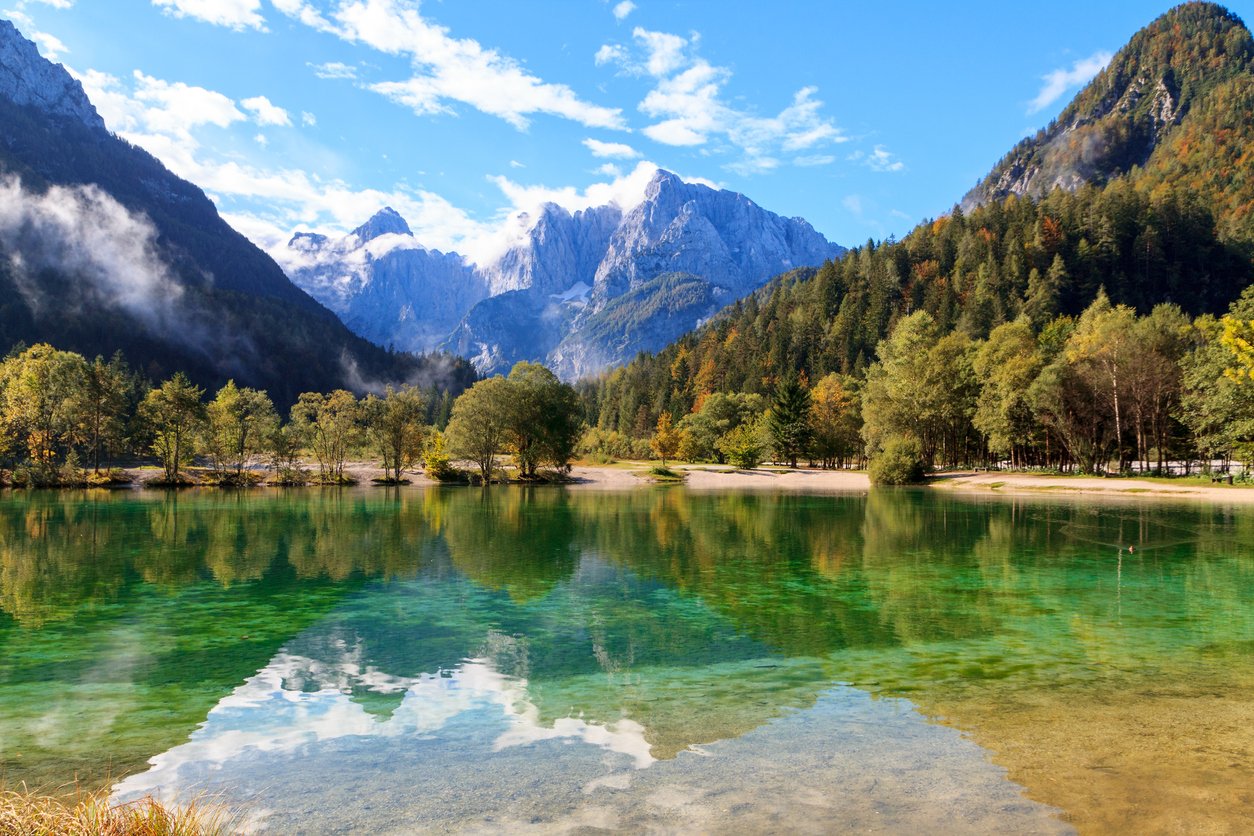 Crystal-clear Lake Jasna in Kranjska Gora with a lofty peak reflected on its surface.
