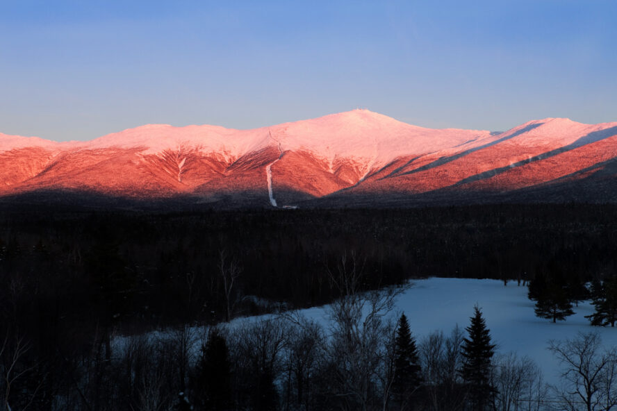 The snowy peaks of Mount Washington dyed pink by the sunrise