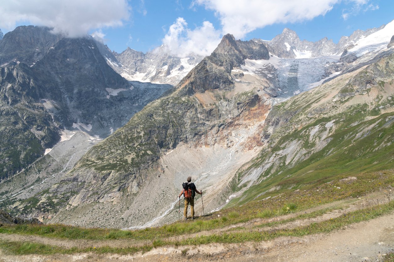 A hiker taking a short break surrounded by rugged Alpine terrain during their Tour du Mont Blanc trek.