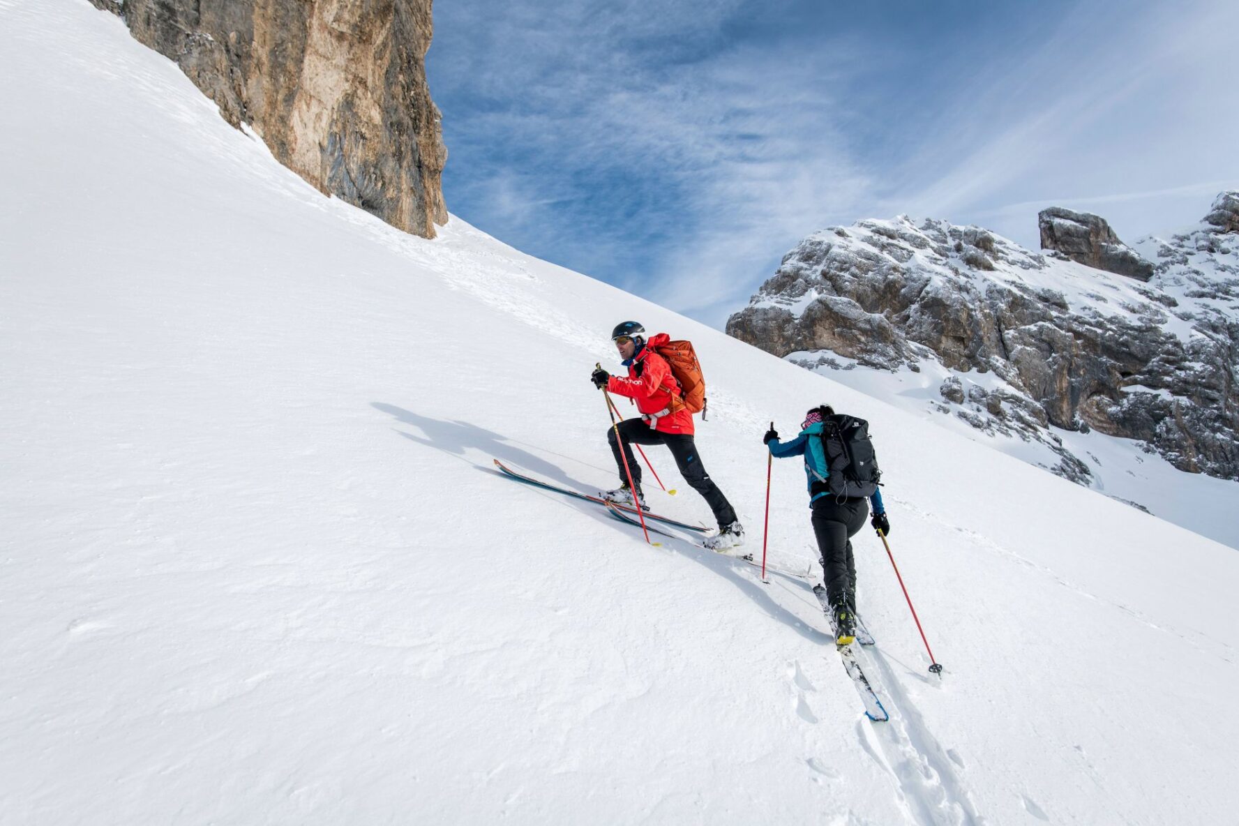 Two backcountry skiers skinning a powder-laden slope in the Brenta Dolomites.