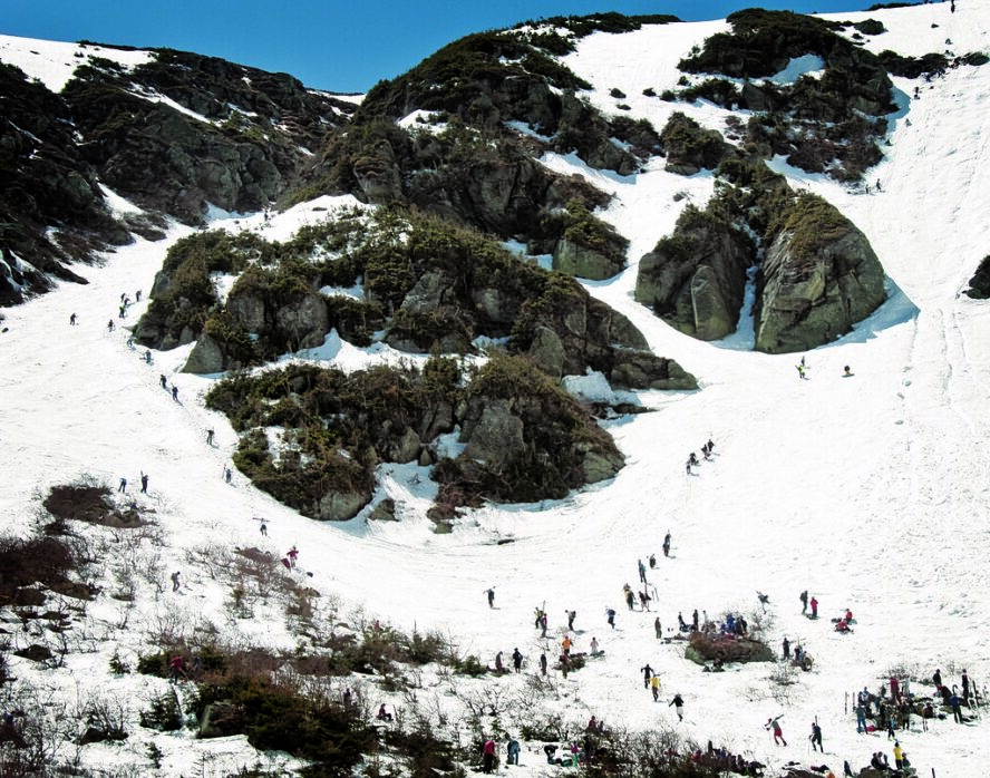 Skiers hiking up the steep slopes of Tuckerman Ravine